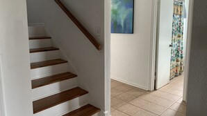A staircase with wooden steps and a handrail, leading to a room with a tiled floor and a door with a colorful curtain. - Beautifully decorated townhome just steps from the beach & Lighthouse (Tybee Island)