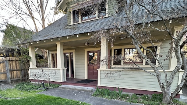 A two-story house with a front porch, a covered entryway, and a small front yard.