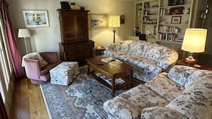 A living room with a sofa, armchair, wooden coffee table, and a patterned rug.