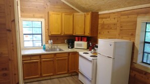 A compact kitchen with wooden cabinets, a sink, a stove, and a refrigerator.