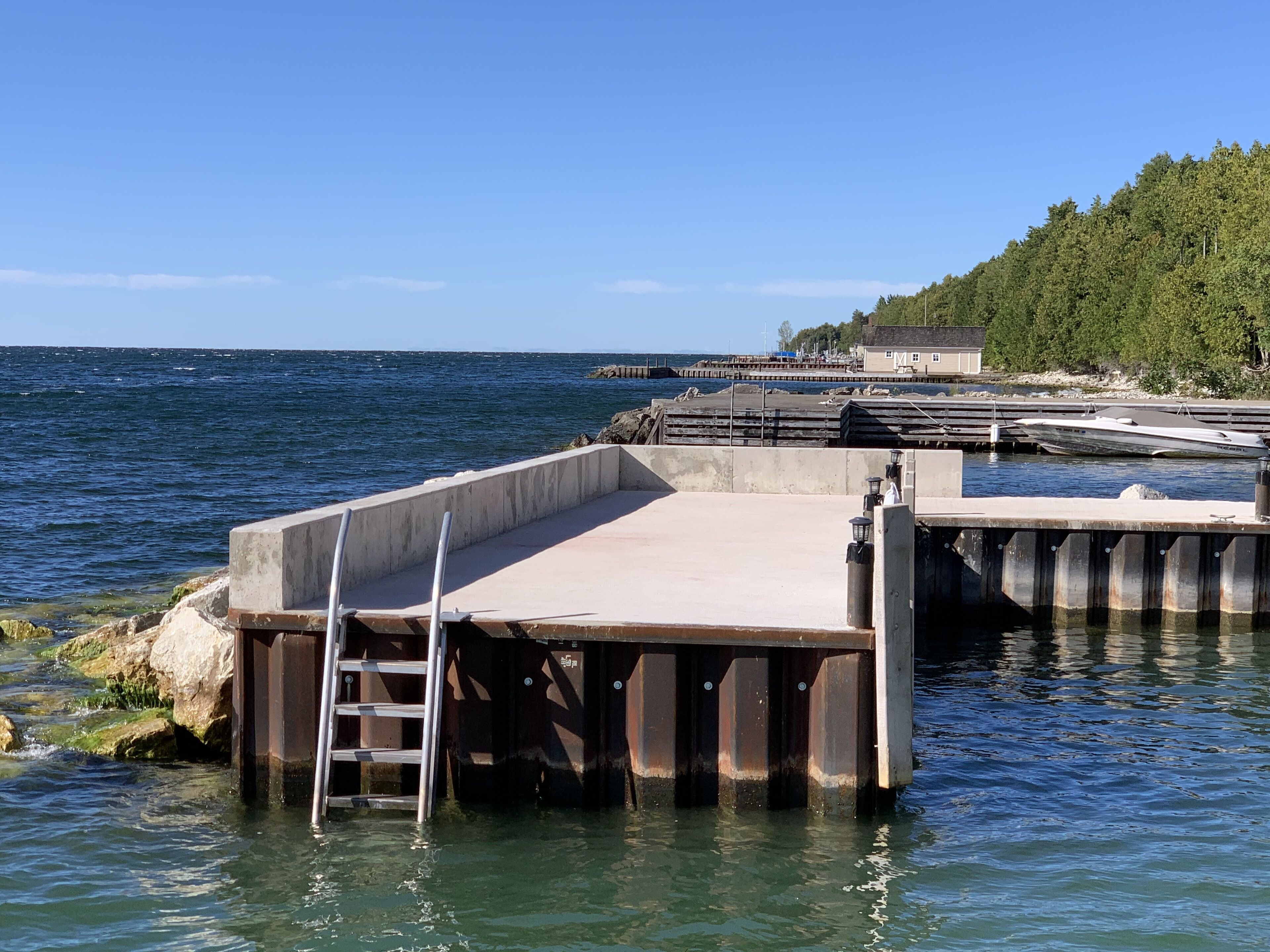 A pier extending into calm waters with a ladder leading down to the dock.