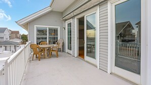 A covered balcony with a table and chairs, large sliding glass doors, and a view of neighboring houses. - Beach Block Rental - Ocean/Beach Out Your Back Door. Great Location At Beach!!! (Point Pleasant Beach)