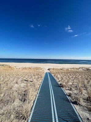 A pathway leading to a beach with a clear sky.
