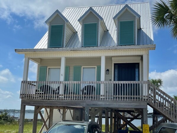 A beachfront house with a balcony, a covered porch, and a garage.