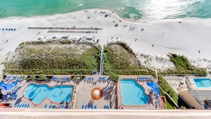 Un resort con varias piscinas, una zona de playa y vistas al océano.