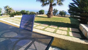 A patio with a metal table and chairs, a palm tree, and a view of the ocean. - Dreamy South Sea View Villa Residence with Pool - Garden Level (Sfakia)