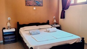 A neatly made bed with white linens and towels, a bedside table with a lamp, a painting of a sunset on the wall, and an air conditioning unit. - Dreamy South Sea View Villa Residence with Pool - Garden Level (Sfakia)