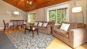 A living room with two sofas, a coffee table, and a dining area with chairs and a table. - Pleasant Beach Getaway - Breathtaking Puget Sound Views and Steps from the Beach (Bainbridge Island)