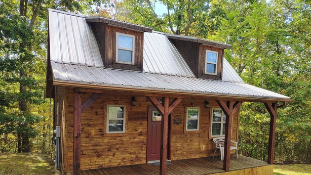 A rustic cabin with a wooden exterior, a porch, and a metal roof. - "The Genoa" a Rustic Adventure - Amish-Built Deluxe Cabin  (Genoa)