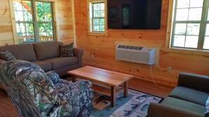 A cozy cabin interior with a sofa, armchair, and a small table. - "The Genoa" a Rustic Adventure - Amish-Built Deluxe Cabin  (Genoa)