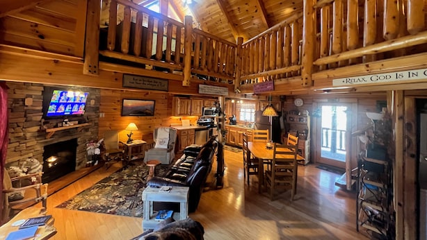 Eine großzügige Lodge mit hohen Decken, Holzbalken, einem Kamin aus Stein, einem Essbereich und einer Küche.