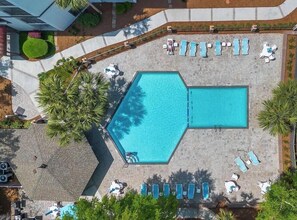 Vista aérea de una piscina con múltiples sillas de descanso y forma hexagonal.