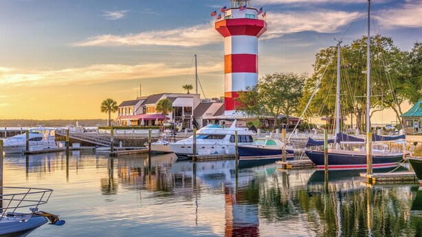 Un phare, un port de plaisance et des bâtiments où sont amarrés des bateaux.