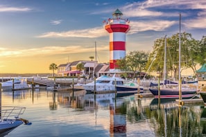 Un faro, un puerto deportivo y edificios con barcos amarrados.