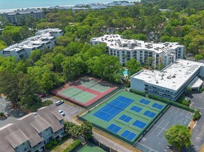 Un edificio de varios pisos con piscina en la azotea y canchas de tenis.