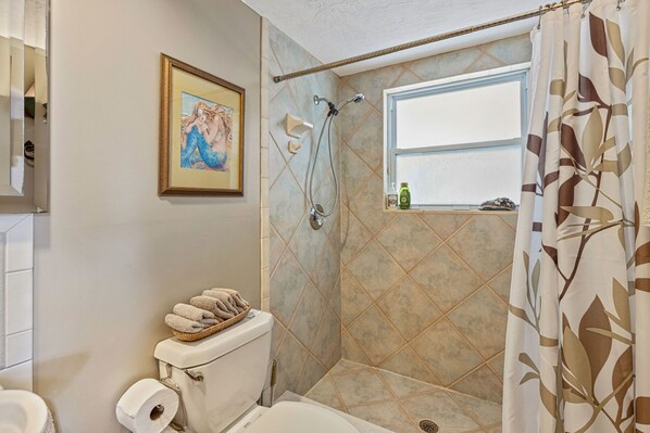 A bathroom with a shower, toilet, and a framed picture on the wall. - Ocean Retreat Beach Front Home--Great Beach-Dog Friendly (St Augustine)