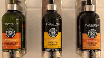 Drie flessen L'OCCITANE producten op een plank.