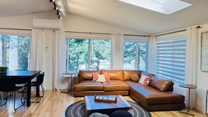 Una sala de estar moderna con un sofá modular, una mesa de comedor y un tragaluz.