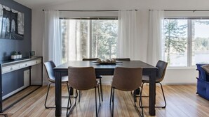 Un comedor con una mesa de madera oscura, cuatro sillas y una ventana con cortinas blancas.