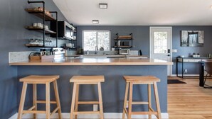 Una cocina moderna con una isla central, taburetes de madera y estantes empotrados.