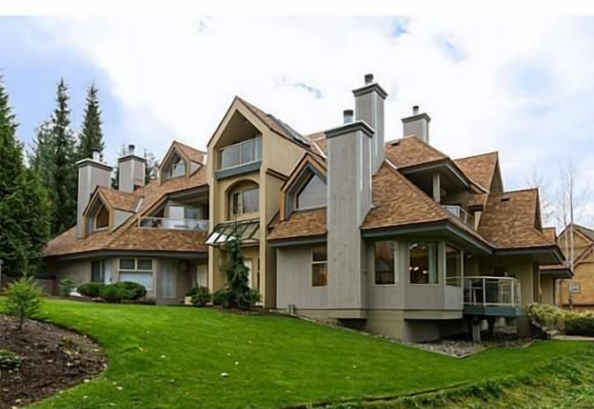Ein mehrstöckiges Haus mit symmetrischer Gestaltung, großen Fenstern und einem gepflegten Rasen.