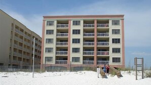 A multi-story building with balconies, located adjacent to a sandy area. - Relax! Put Your toes in the Sand at this DIRECT GULF FRONT CONDO   (Orange Beach)