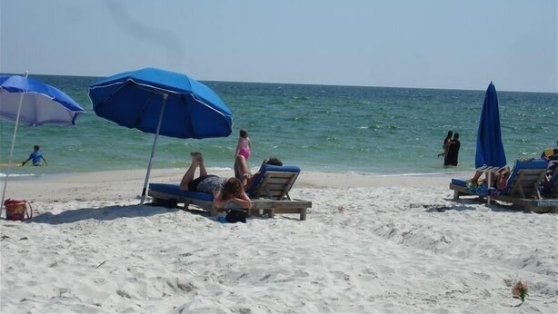 A beach with several lounge chairs and blue umbrellas. - Relax! Put Your toes in the Sand at this DIRECT GULF FRONT CONDO   (Orange Beach)