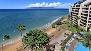 Un hotel frente a la playa con piscina, sillas de playa y vista al océano.