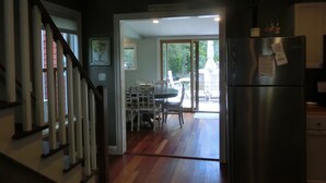 A kitchen with a stainless steel refrigerator, wooden flooring, and a dining area with a table and chairs. - Quaint,,,Quiet..up island feel yet a short walk to town and harbor (Oak Bluffs)