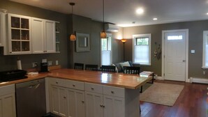 A kitchen with white cabinets, a wooden island, and pendant lighting. - Quaint,,,Quiet..up island feel yet a short walk to town and harbor (Oak Bluffs)