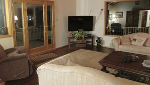 A living room with a sofa, a coffee table, a television, and a sliding glass door leading to an outdoor area.