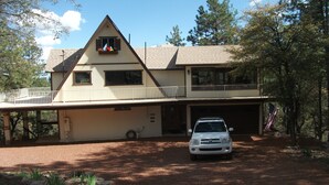 A two-story lodge with a balcony, a covered driveway, and a white car parked in front.