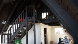 A staircase with a wooden railing leading to a loft area.