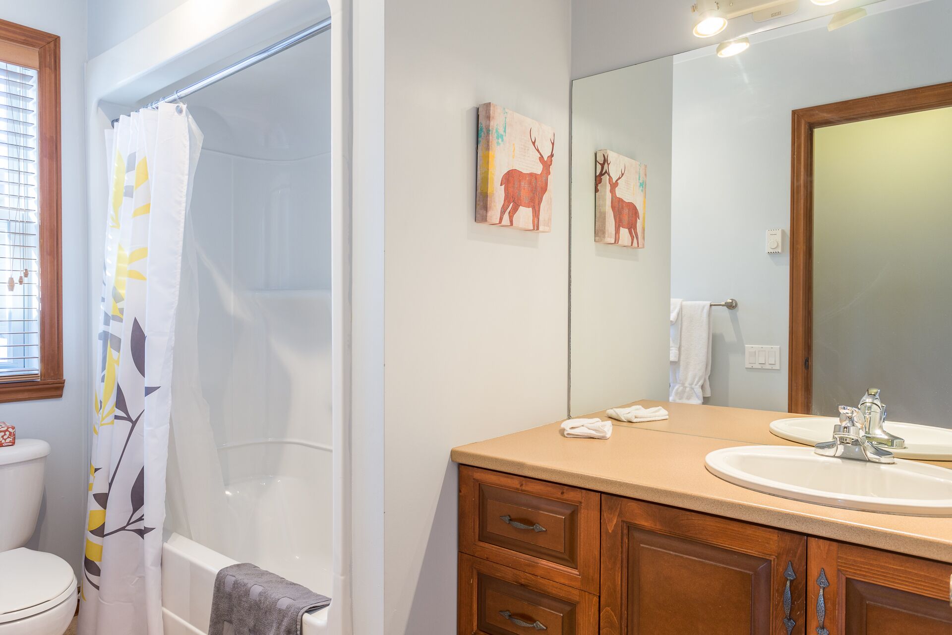 Un baño con ducha, inodoro, lavabo y armarios de madera.