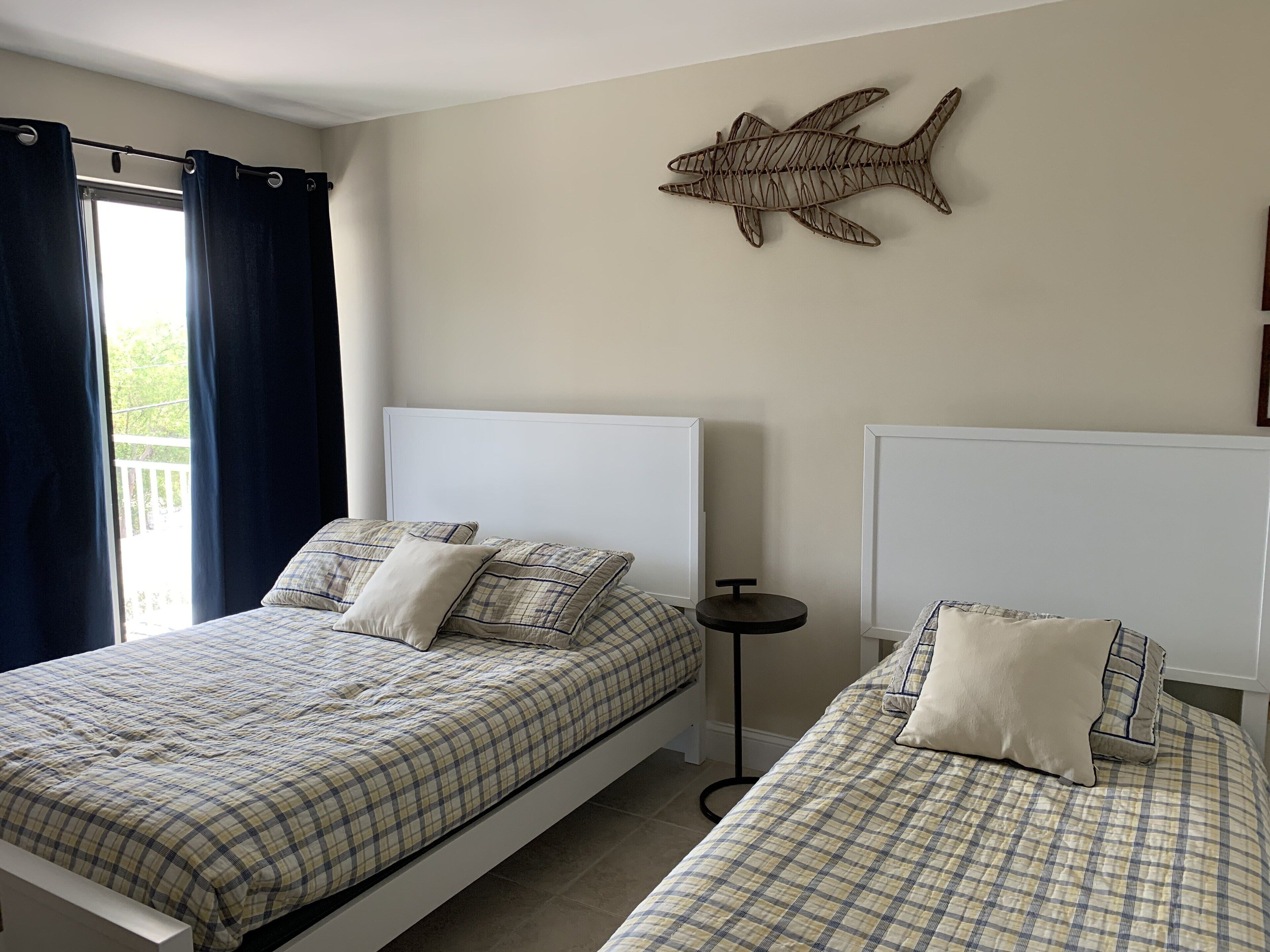 Une chambre avec deux lits, une petite table ronde et une décoration murale représentant des poissons.