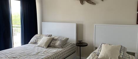A bedroom with two beds, a small round table, and a wall-mounted fish decoration.