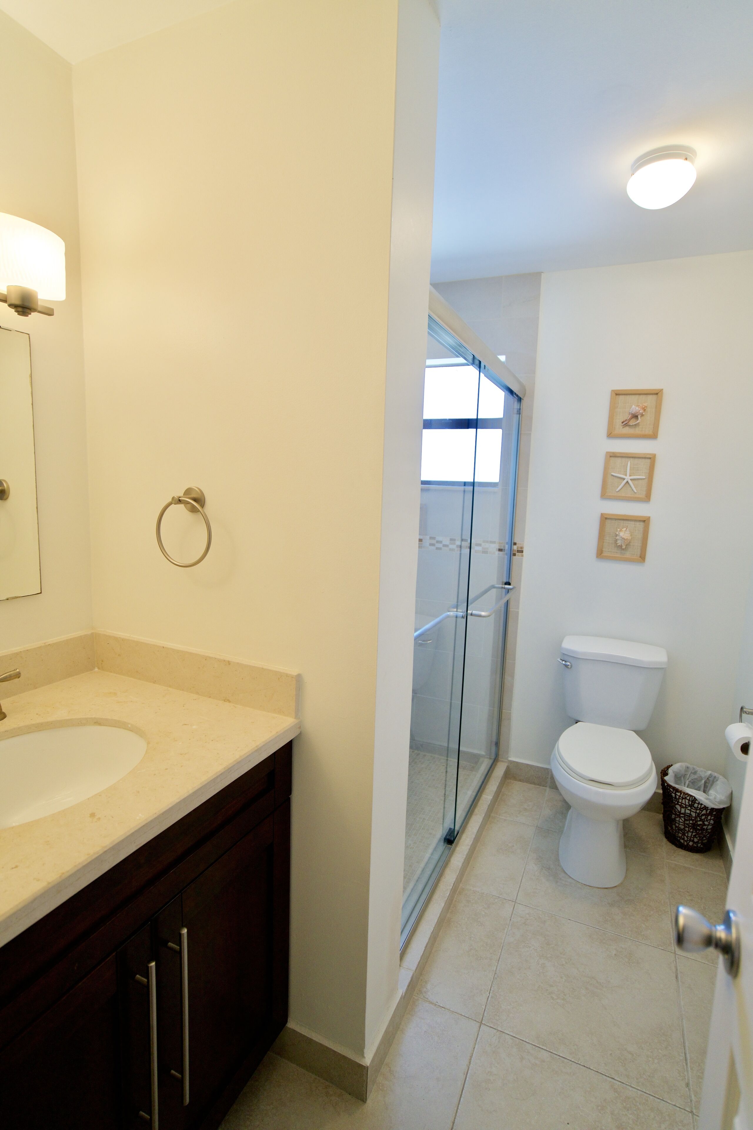 A bathroom with a sink, mirror, toilet, and glass shower enclosure.