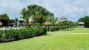 A resort with a swimming pool, palm trees, and thatched-roof structures. - Updated Key Largo Townhome • Pool • Saltwater Lagoon • Beach • Oceanfront Access (Key Largo)
