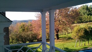 A porch with white columns, a brick wall, and a view of trees and a grassy hill. - Destination, Overlooking Cooperstown, Large Grounds, 6.2 miles from Dreams Park. (COOPERSTOWN)