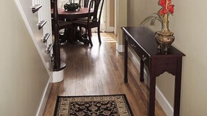 A hallway with a wooden floor, a dining table with chairs, a console table with a vase, and a staircase with white railings. - Destination, Overlooking Cooperstown, Large Grounds, 6.2 miles from Dreams Park. (COOPERSTOWN)