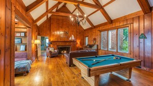 Een houten interieur met een pooltafel, een open haard en een gezellige zithoek.