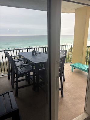 Un balcone con tavolo e sedie, vista sull'oceano e una spiaggia sullo sfondo.