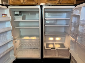 An open refrigerator with multiple shelves and drawers, a freezer compartment, and a water dispenser.