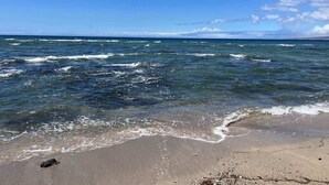 Une plage avec une eau d’un bleu limpide et un rivage sablonneux.
