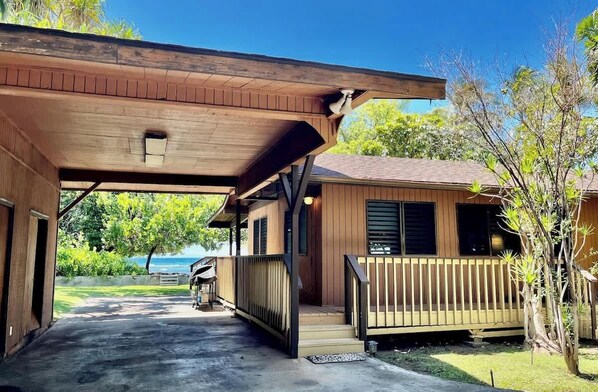 Un espace extérieur abrité, doté d’une construction en bois, d’un chemin en béton et offrant une vue sur l’océan.