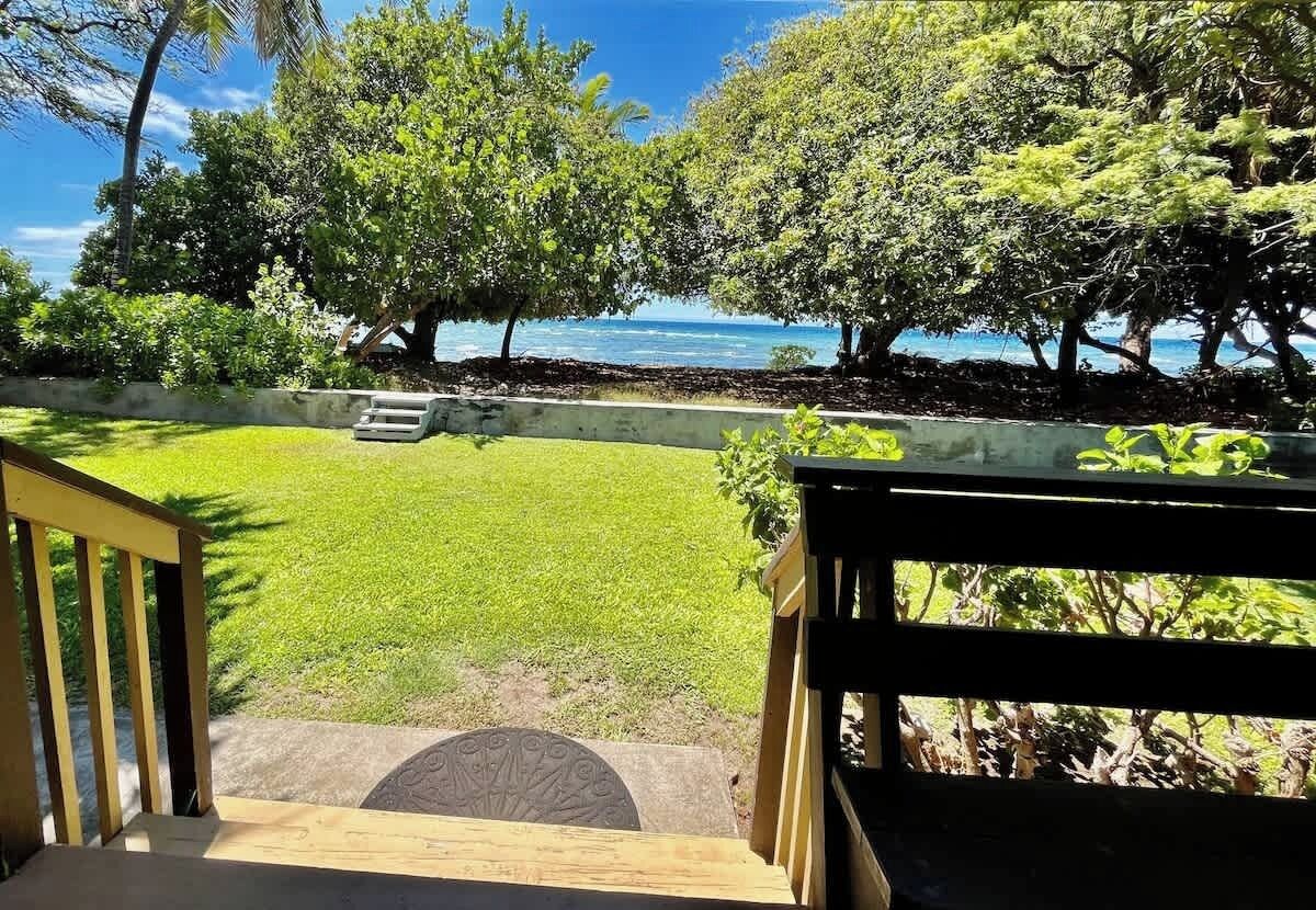 A view from a balcony overlooking a grassy area with trees and a body of water.