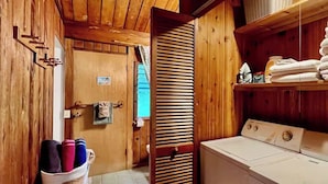 Une buanderie avec des murs en bois, un lave-linge et un étendoir sur lequel sont pliées des serviettes.