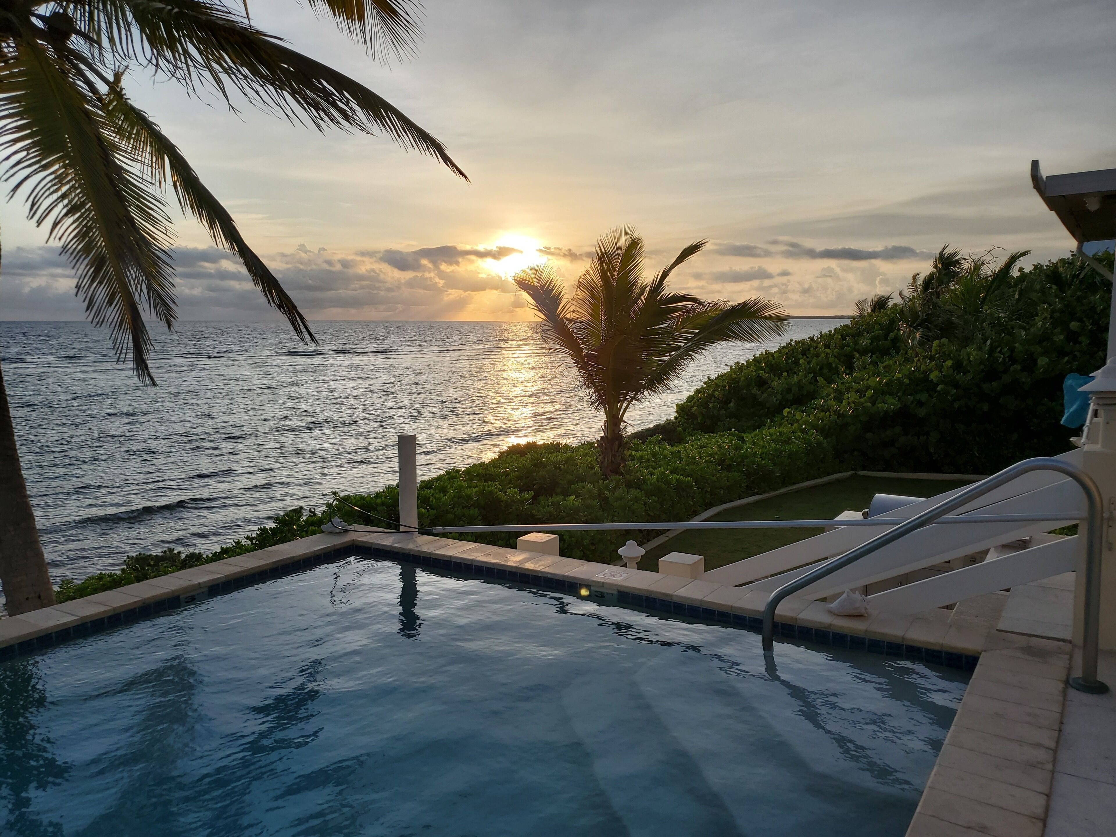 A pool with a view of the ocean and sunset.