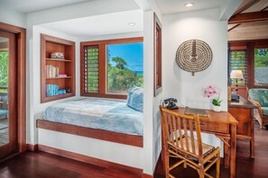 Quarto com janela embutida, estantes de madeira, escrivaninha com cadeira e um elemento decorativo na parede.