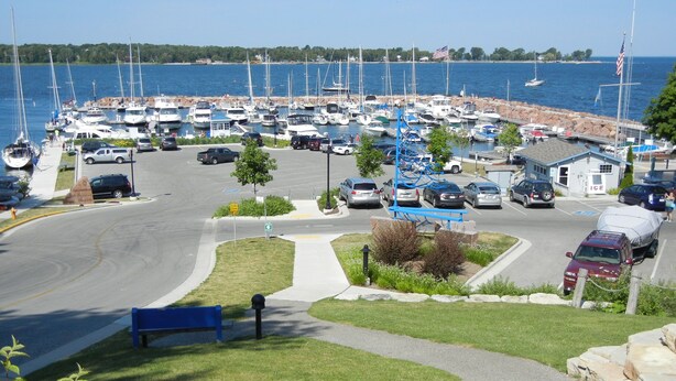 Un puerto deportivo con barcos amarrados, un estacionamiento y un pequeño edificio con la leyenda 'ICE'.